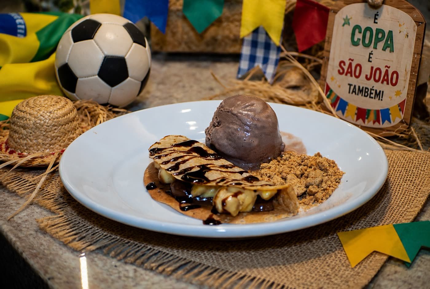 Crepe doce com sorvete e calda de chocolate em decoração de Copa e São João