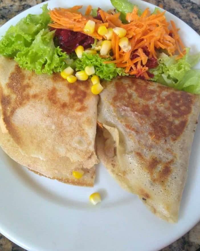 Crepe dourado cortado ao meio com salada colorida