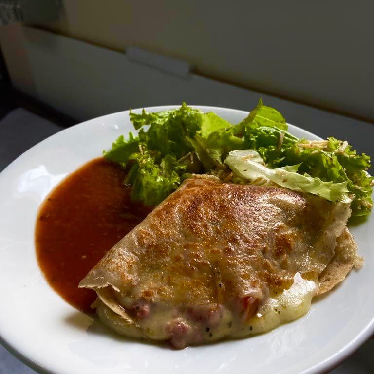 Crepe com queijo derretido, molho e folhas de alface