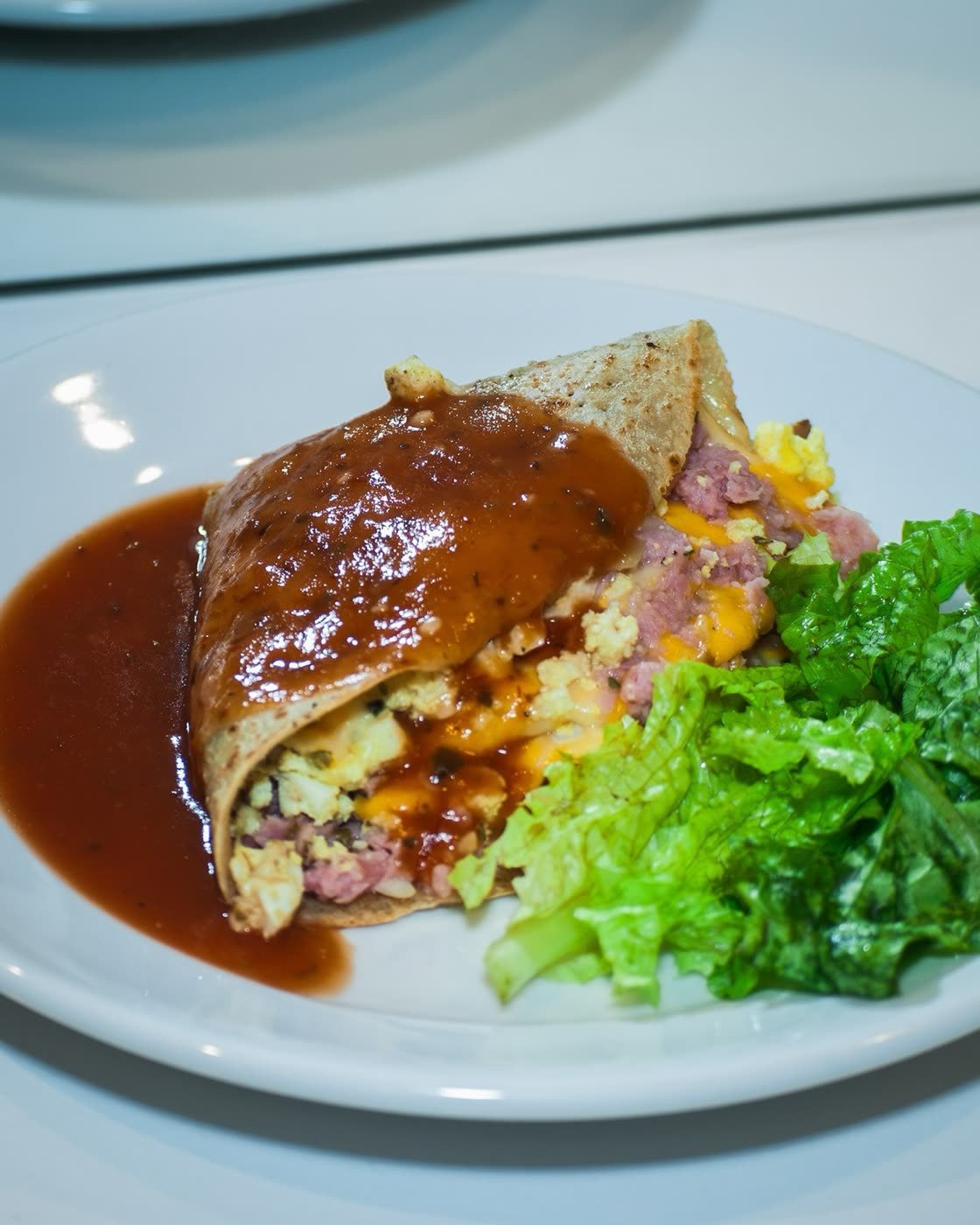 Crepe recheado com presunto, ovos e queijo, coberto com molho