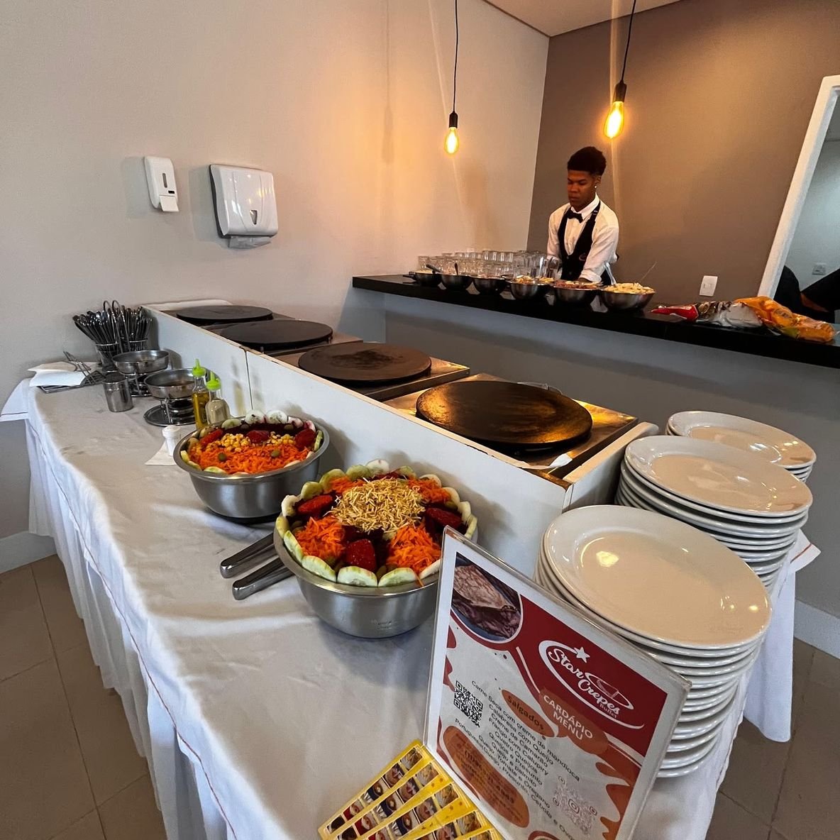 Estação de crepes montada no salão com chapas e saladas
