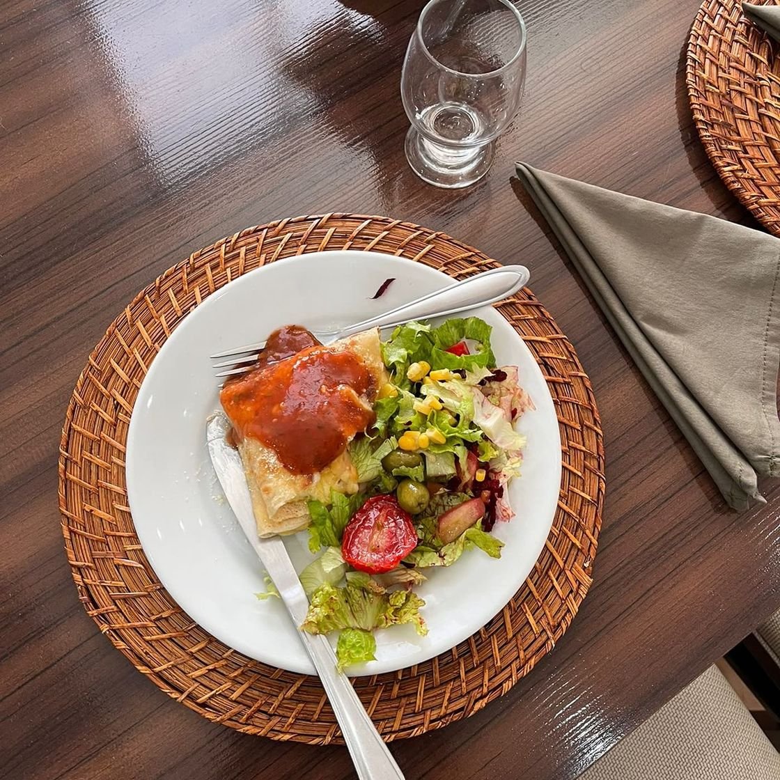 Crepe com molho e salada servido em mesa posta