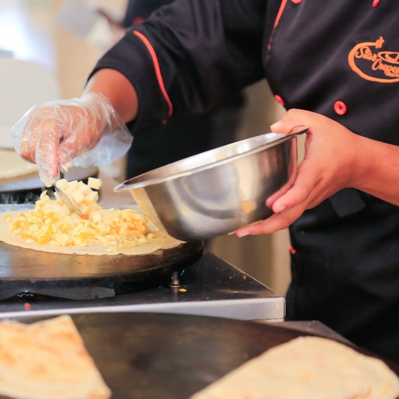 Profissional Star Crepes adicionando recheio ao crepe na chapa