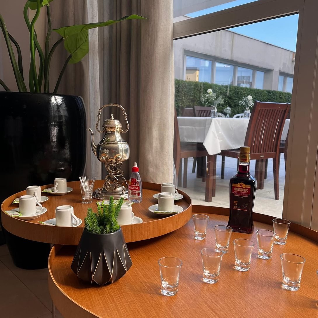 Mesa de café com bule de prata, xícaras e licor